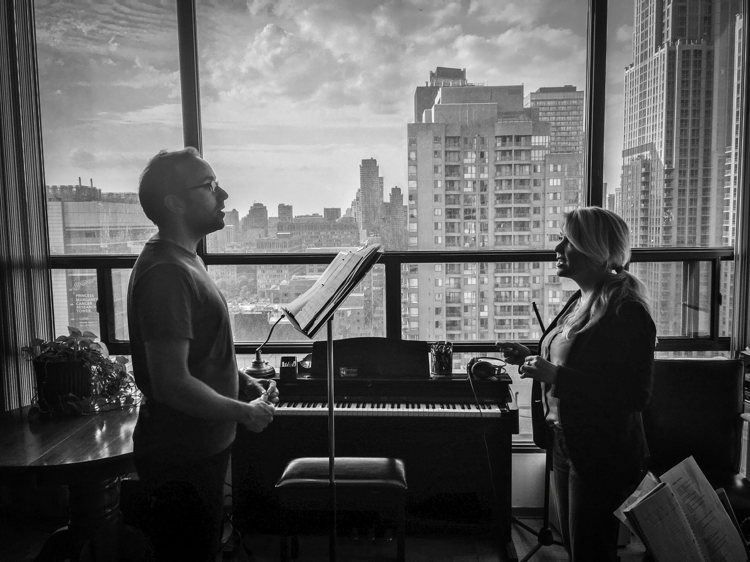 Woman giving a singing lesson to a man in a city apartment