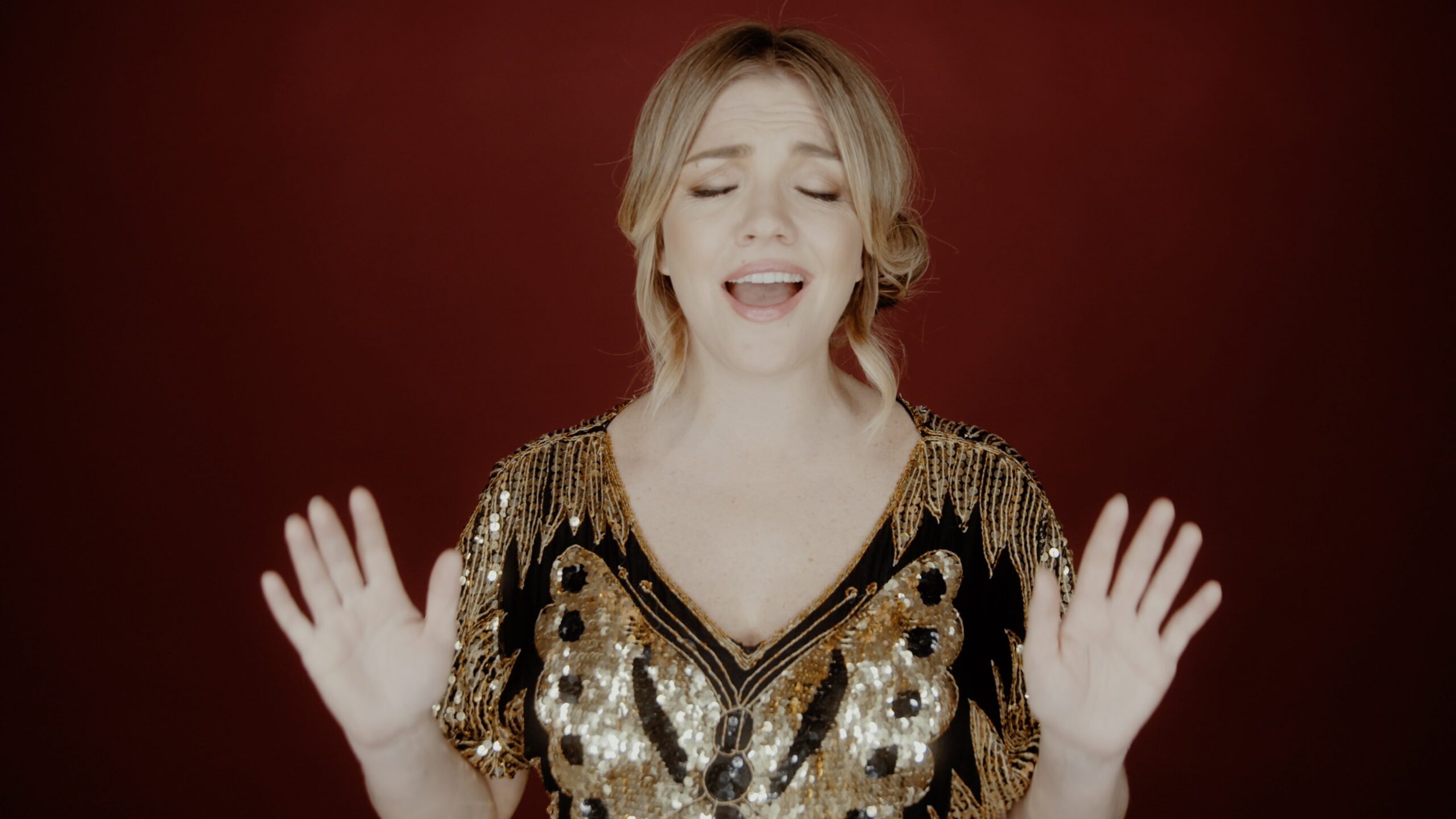 Annie Bonsignore on red background, singing