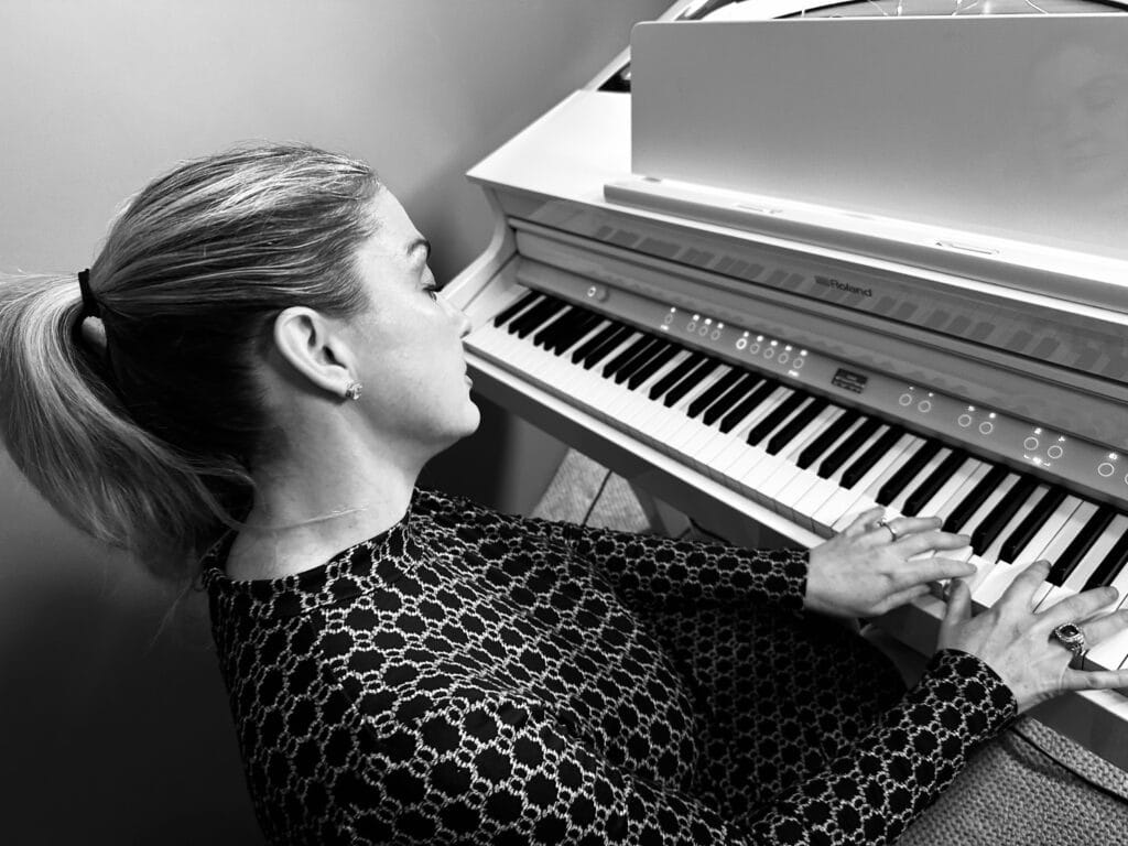 A female piano teacher and pianist at a white baby grand piano