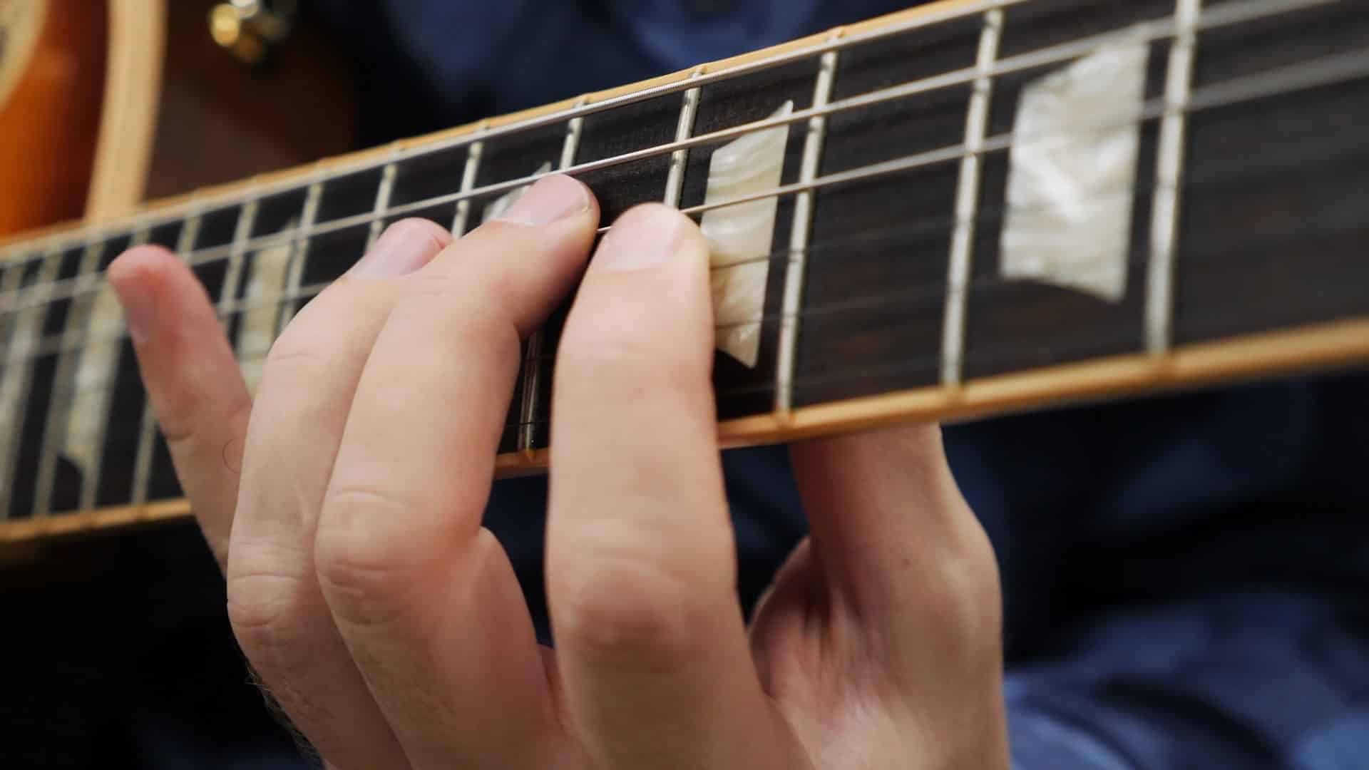 Close-up of a student's hand fretting chords during a private guitar lesson at Annie Bonsignore Studios